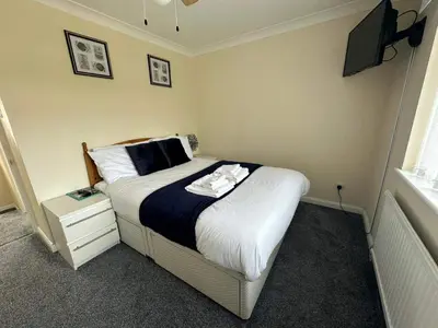 a bedroom with a bed with a tv on the wall at 4 Bed House - Sleeps 8 - Pets - Parking - Wifi in Great Clacton