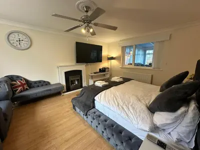a bedroom with a bed and a couch and a clock at 4 Bed House - Sleeps 8 - Pets - Parking - Wifi in Great Clacton