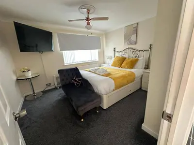 a bedroom with a bed and a chair and a television at 4 Bed House - Sleeps 8 - Pets - Parking - Wifi in Great Clacton