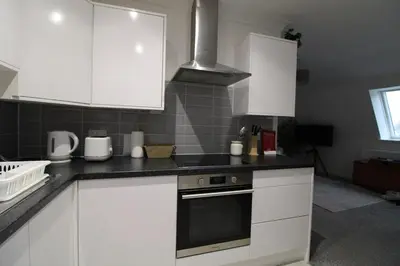 a kitchen with white cabinets and a stove top oven at Colchester Roof Top Flat - Central, Business, Travel in Colchester