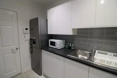 a kitchen with white cabinets and a sink and a microwave at Colchester Roof Top Flat - Central, Business, Travel in Colchester
