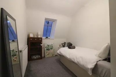 a bedroom with a bed and two windows and a mirror at Colchester Roof Top Flat - Central, Business, Travel in Colchester
