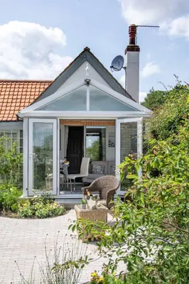 a house with a conservatory with a patio at Quayside Cottage in Waldringfield