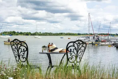 a table with two chairs in front of a marina at Quayside Cottage in Waldringfield