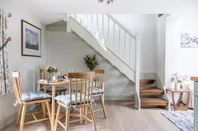 a dining room with a table and chairs and a staircase at The Boathouse in Waldringfield