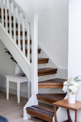 a staircase in a home with white walls and wooden floors at The Boathouse in Waldringfield