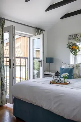 a bedroom with a large bed and a balcony at The Boathouse in Waldringfield