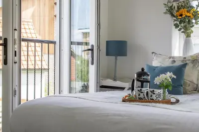 a bedroom with a white bed with a window at The Boathouse in Waldringfield