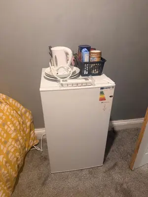 a small white refrigerator with a basket on top of it at Single room in Canvey island in Hadleigh
