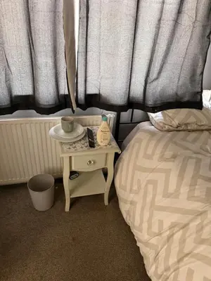 a bed with a night stand next to a bed with a bedskirts at Single room in Canvey island in Hadleigh