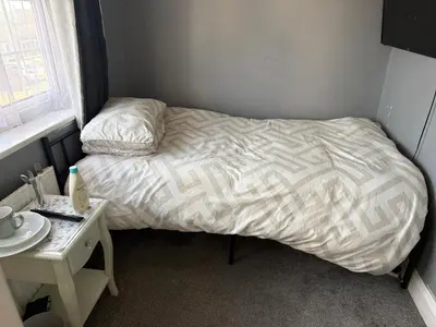 a small bed in a small room with a table at Single room in Canvey island in Hadleigh