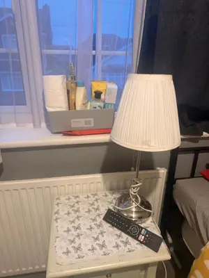 a table with a lamp and a remote control on it at Single room in Canvey island in Hadleigh