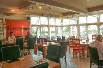 a restaurant with tables and chairs and people sitting at them at The Victory at Mersea in West Mersea