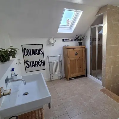 a bathroom with a sink and a shower and a window at The Old Stables in Felixstowe