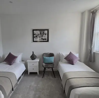 a bedroom with two twin beds and a chair at The Old Stables in Felixstowe