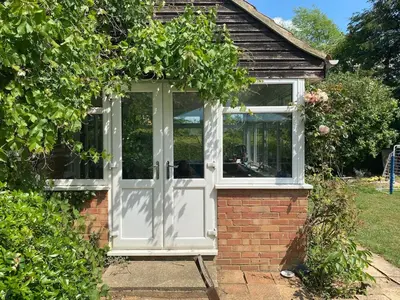 a greenhouse with a white door in a garden at Family Country Home in Stoke Ferry