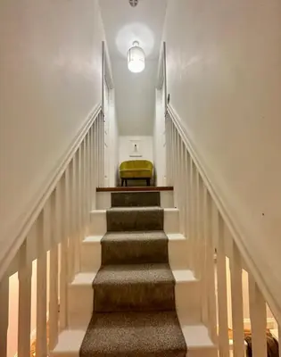 a stairway with a yellow ottoman in the middle at Haggard House Stock in Stock