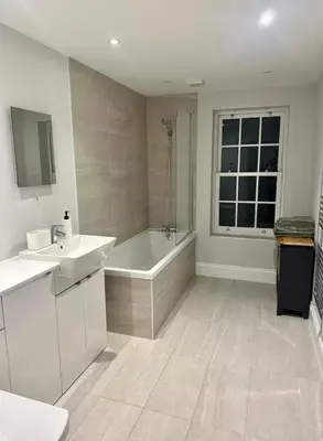 a white bathroom with a tub and a sink at Haggard House Stock in Stock