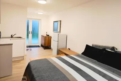 a bedroom with a bed and a kitchen with a refrigerator at 1 Bed LuxuryHouse- Sleeps 2- Garden Wifi Parking in Hornchurch