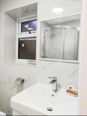 a bathroom with a sink and a mirror and a tv at 1 Bed LuxuryHouse- Sleeps 2- Garden Wifi Parking in Hornchurch