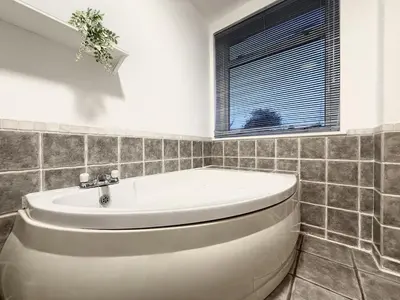 a white bath tub in a bathroom with a window at 2 bed house secure parking Sleeps 6 in Ipswich