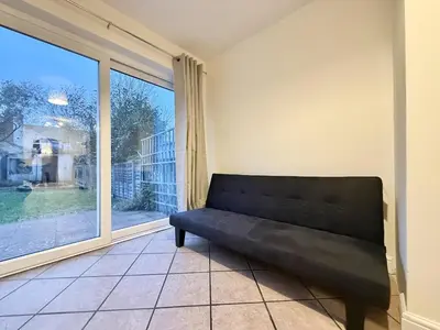 a black couch in a room with a large window at 2 bed house secure parking Sleeps 6 in Ipswich