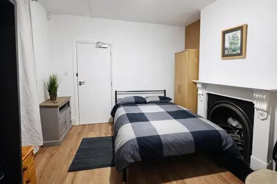 a bedroom with a black and white bed and a fireplace at landvue stays, The Colchester town White House 4 bed 2 bath! in Mundon
