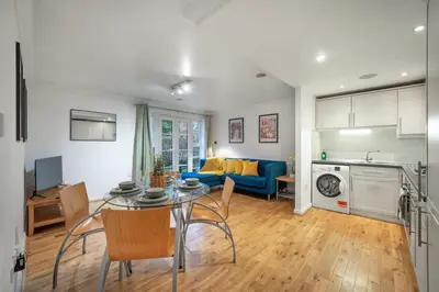 a living room with a table and a blue couch at Bishops Stortford 2 Bed Flat - Free Parking - STN in Bishops Stortford
