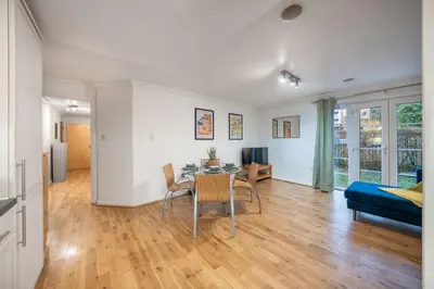 a living room with a table and a blue couch at Bishops Stortford 2 Bed Flat - Free Parking - STN in Bishops Stortford