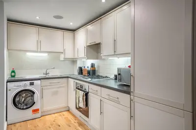 a kitchen with white cabinets and a washer and dryer at Bishops Stortford 2 Bed Flat - Free Parking - STN in Bishops Stortford