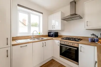 a kitchen with white cabinets and a sink and a stove at Dray Cottage, Leiston, near Sizewell - Ideal for a short or long term corporate lets - Managed by Aldeburgh Coastal Cottages in Leiston