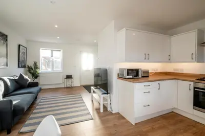 a kitchen and living room with white cabinets and a couch at Garden Cottage, Leiston, near Sizewell - Ideal for a short or long term corporate lets - Managed by Aldeburgh Coastal Cottages in Leiston