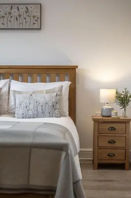 a bedroom with a bed and a night stand with a lamp at Greenacres in Kelsale