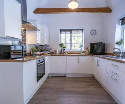 a large kitchen with white cabinets and a window at Greenacres in Kelsale