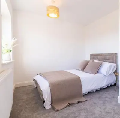 a bedroom with a bed with white sheets and pillows at Margrets Crescent in Leiston