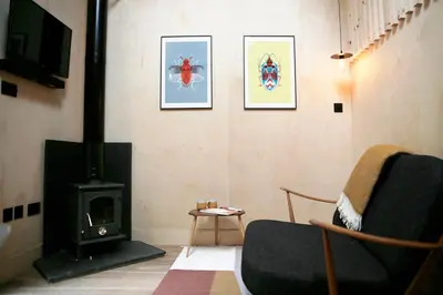 a living room with a stove and a chair at Gazebo Lodge in Martlesham