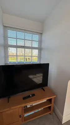a large flat screen tv sitting on a wooden entertainment center at The Coach House WPH, Epping in Epping
