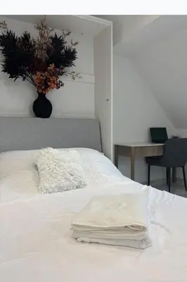 a white bed with a vase of flowers on it at Lavish The White Apartment in Bury Saint Edmunds