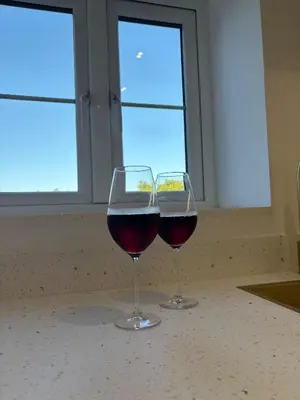 two glasses of red wine sitting on a counter at Lavish The White Apartment in Bury Saint Edmunds