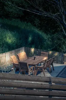 a wooden picnic table with three wooden chairs around it at Buzzards Retreat in Larling