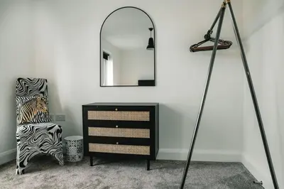 a room with a black dresser and a mirror at Norwich New 3 Bedroom Townhouse Close to NNUH UEA