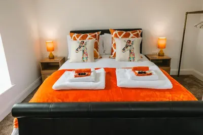 a bedroom with a bed with two towels and two lamps at Norwich New 3 Bedroom Townhouse Close to NNUH UEA