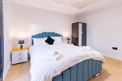 a bedroom with a large bed with a blue headboard at Hamlet Hideaway Sleeps 14 Off Street Parking - Pass the Keys in Westcliff On Sea