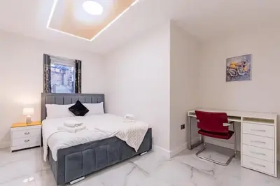 a bedroom with a bed and a desk and a red chair at Hamlet Hideaway Sleeps 14 Off Street Parking - Pass the Keys in Westcliff On Sea