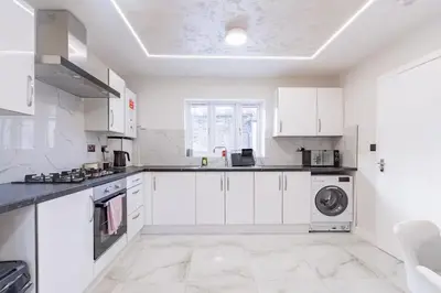 a white kitchen with white cabinets and a washing machine at Hamlet Hideaway Sleeps 14 Off Street Parking - Pass the Keys in Westcliff On Sea