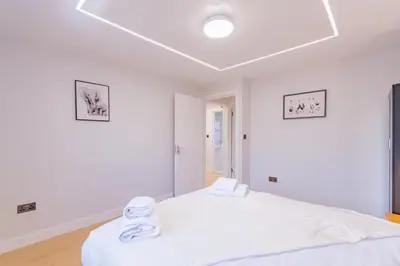 a white bedroom with two white beds in it at Hamlet Hideaway Sleeps 14 Off Street Parking - Pass the Keys in Westcliff On Sea