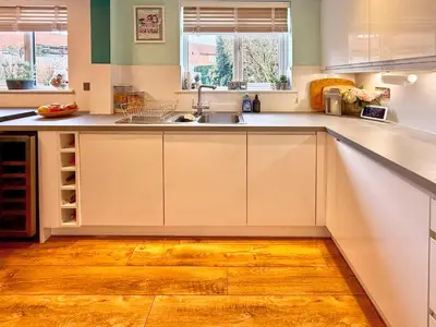 a kitchen with white cabinets and a wooden floor at Charming 3 bedroom house in Chelmsford in Chelmsford