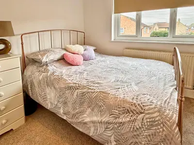 a bedroom with a bed with pillows and a window at Charming 3 bedroom house in Chelmsford in Chelmsford