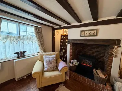 a living room with a fireplace and a chair at Pretty Cottage in Harleston, Norfolk, dog friendly in Harleston