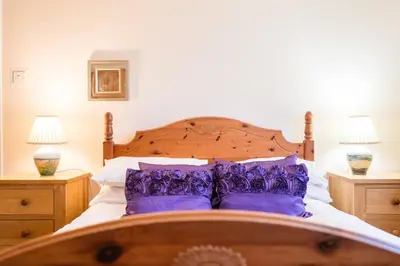 a bedroom with a large bed with purple pillows at 1 Hall Farm Cottage, Aldeburgh in Aldeburgh